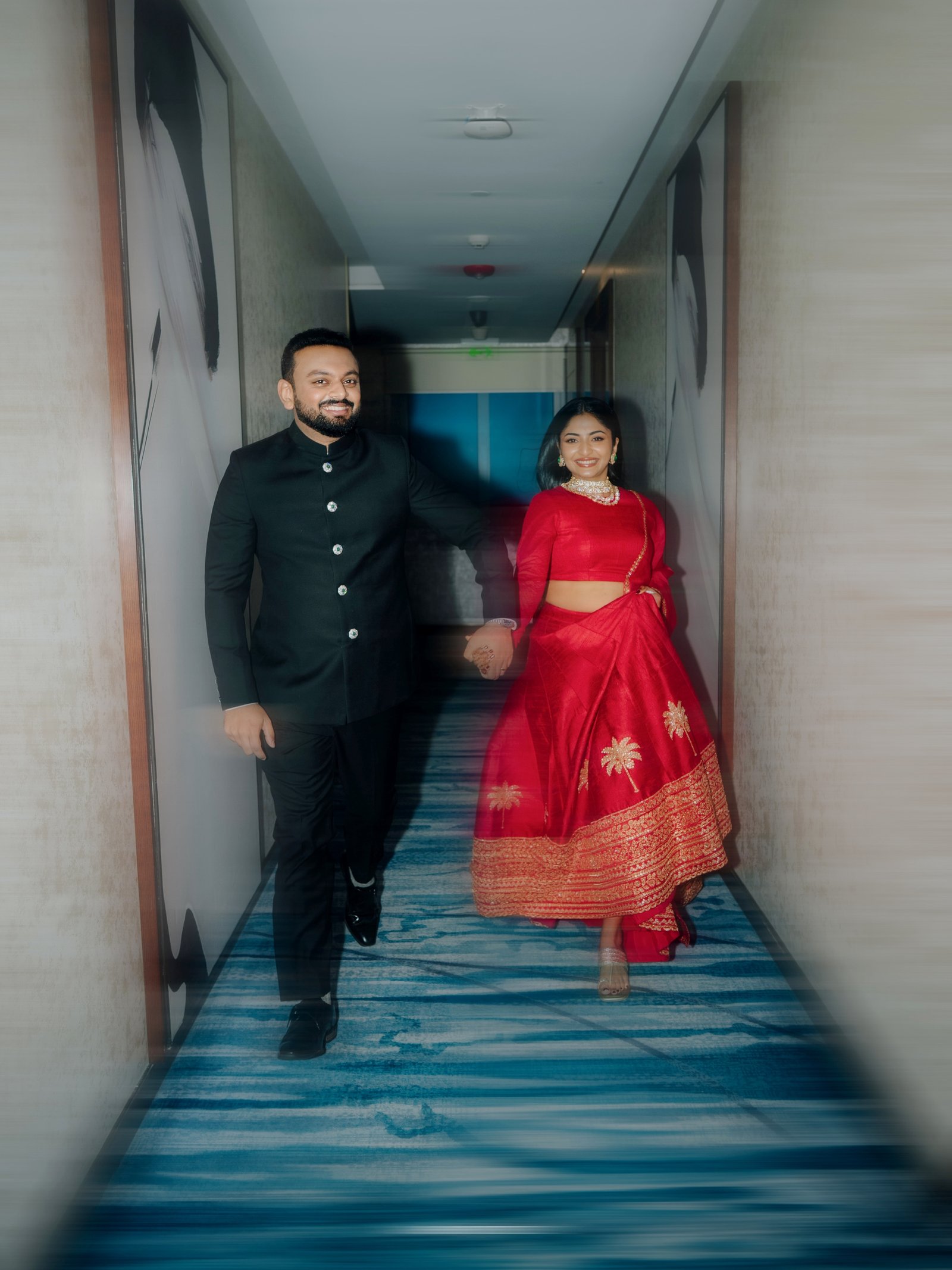 A couple walking together in crimson lehenga and royal sherwani