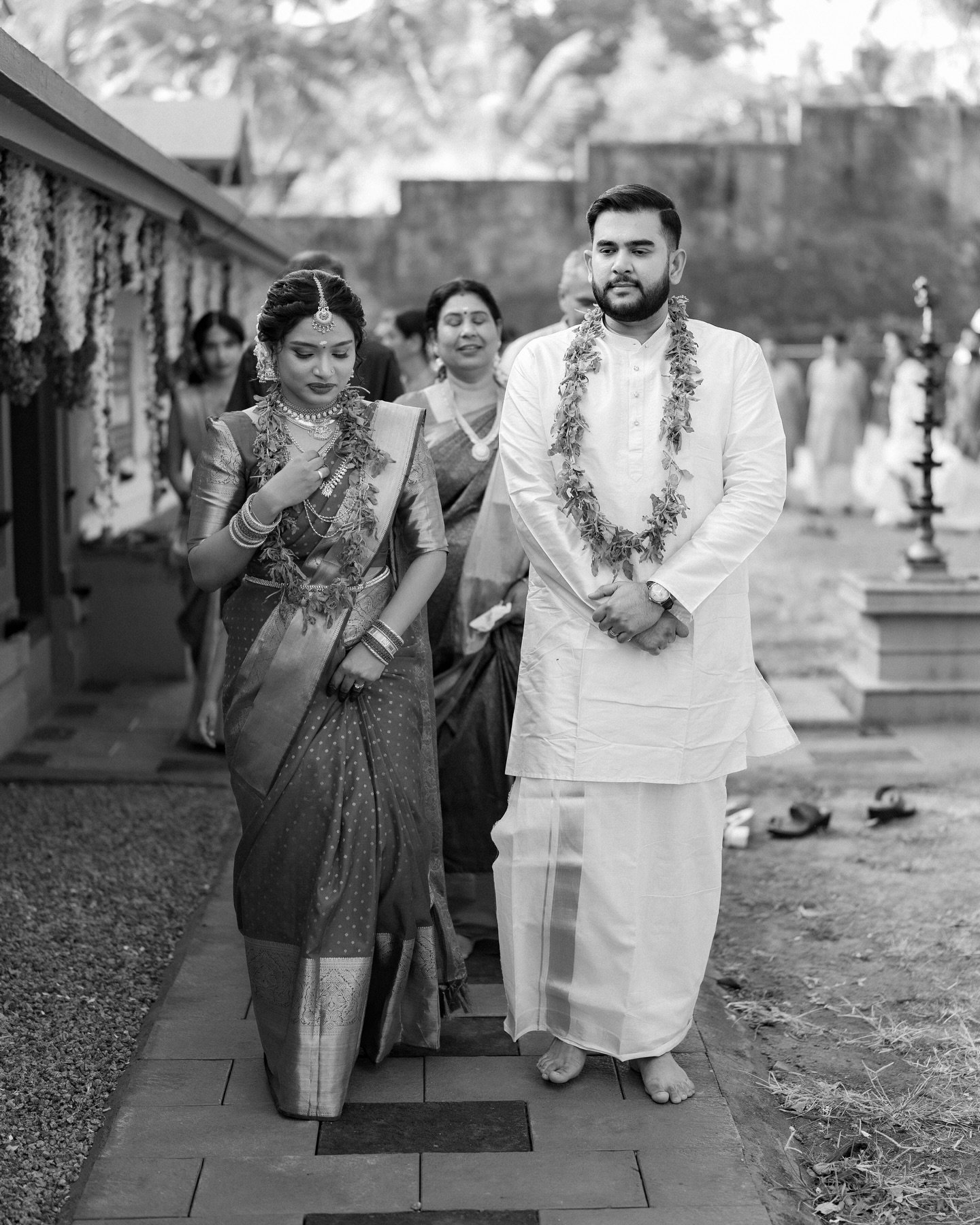 A couple in ceremonial attire walking together in classic monochrome
